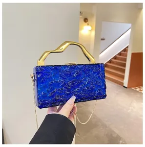 Vista dettagliata della borsa da sera in acrilico blu testurizzato con manico dorato.