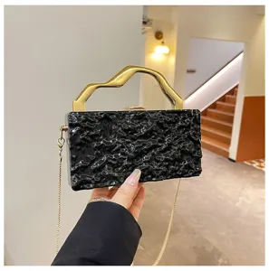 Borsa pochette nera strutturata con manico dorato astratto e catena per festa serale.