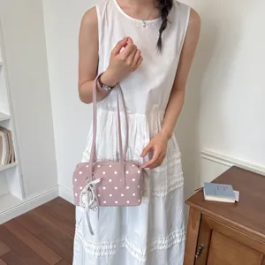 Detalle de primer plano del elegante bolso de bolos de lunares rosas con correas dobles y dije.