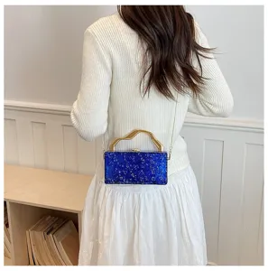 Vista dettagliata di una elegante pochette rigida in marmo blu con un manico dorato unico.