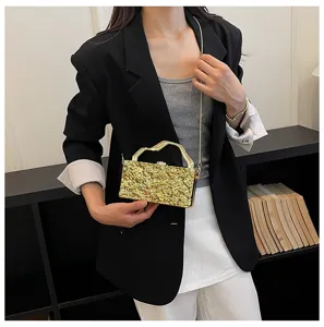 Scatto dettagliato di pochette a mano con texture metallica, catena e manico elegante.
