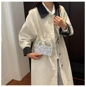 Vista dettagliata della borsa pochette in metallo testurizzato con manico e catena.