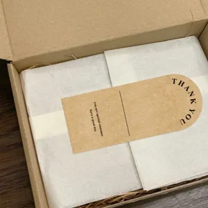 Kraft paper airplane box detail, showing packaging paper, raffia and thank you card insert.