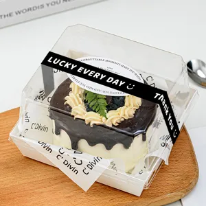 Vista dettagliata di una scatola trasparente per dolci con adesivi eleganti e torta al cioccolato.