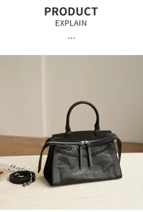 Detail view of black vintage leather handbag featuring braided handles and front zipper.