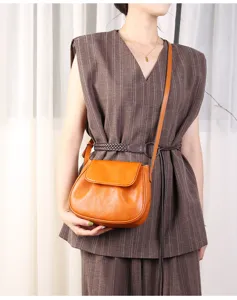 Detail view of stylish orange leather saddle crossbody bag worn by model, premium aesthetic.