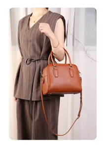 Stylish brown leather Boston bag with top handles and adjustable strap for women commuting.