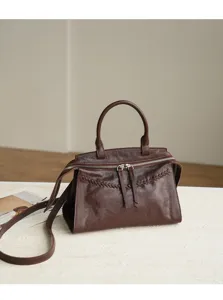 Detailed view of the dark brown leather handbag showing fine texture and woven front accent.