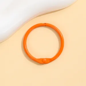 Close-up detail of the vibrant orange baked paint metal loose leaf ring, showing smooth finish.