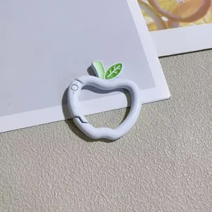 Close-up detail shot of cute apple-shaped spring ring keychain with green leaf accent.