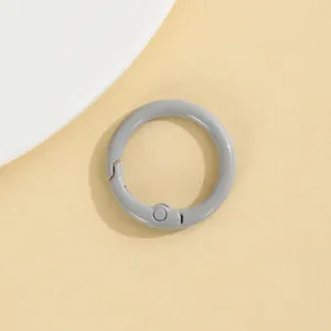 Gedetailleerd overzicht van grijze ronde veerring, zinklegering karabijnhaak op beige.