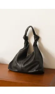 Detailed view of black soft leather hobo bag with knotted handle, elegant daily accessory.