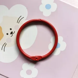 Gros plan sur l'anneau de reliure en métal rouge, finition colorée lisse, accessoire DIY.