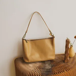 Detailed view of minimalist camel leather shoulder bag, elegant casual dumpling design.