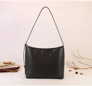 Detail view of a minimalist dark brown soft leather shoulder bag in a cozy vintage setting.