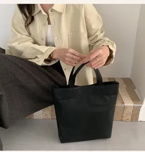 Minimalist black tote bag detail featuring durable handles and spacious interior for daily use.