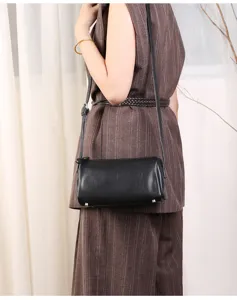 Minimalist black leather cylindrical shoulder bag, detailed view of the stylish barrel shape.