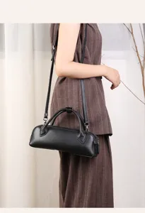 Detail view of a stylish black leather boston bag worn on shoulder, showcasing premium texture.