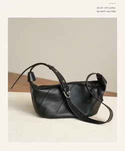 Detail shot of black leather dumpling shoulder bag, elegant curved design with smooth texture.