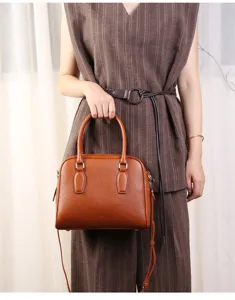 Brown leather Boston bag detail, classic bowling handbag with top handles and shoulder strap.