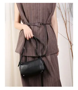 Detail view of black leather cylinder barrel bag, compact shoulder strap, daily accessory design.