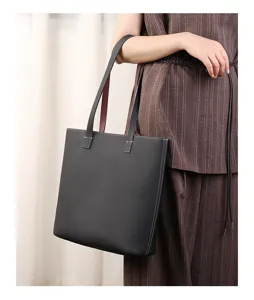 Detail view of black leather tote bag, showcasing texture and double shoulder straps.