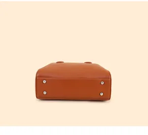 Detailed bottom view of the brown leather Boston handbag featuring four durable metal protective feet.