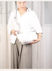 Detail view of a minimalist white hobo shoulder bag worn by model, simple chic daily fashion.