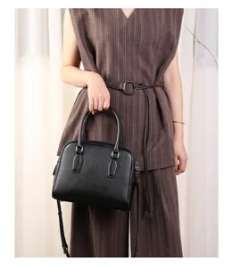 Detailed view of a stylish black leather boston handbag with metal hardware and dual handles.