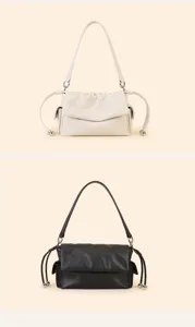 Detail view of stylish minimalist pleated shoulder bag with drawstring and metallic ball accents.