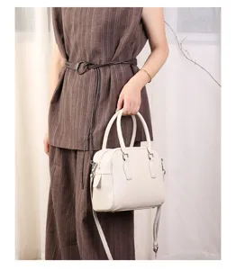 Detailed view of off-white leather Boston shoulder bag with dual top handles and metal hardware.