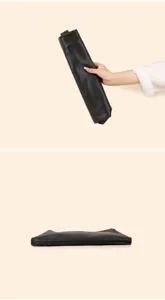Black leather clutch bag detail shot showcasing soft texture and flexible folding design.