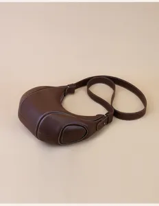 Brown leather croissant shoulder bag detail, stylish crescent moon design with contrast stitching.