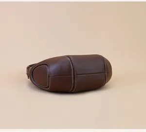 Brown top-layer cowhide crescent underarm shoulder bag detail shot with contrast white stitching.
