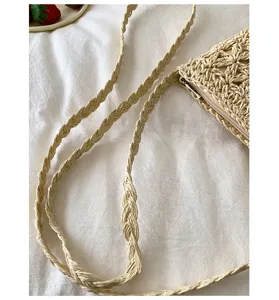 Vista detallada en primer plano de un bolso cruzado de paja tejida en color beige con correa.