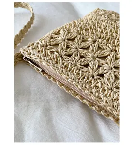 Primer plano detallado del bolso cruzado de paja tejida con textura fina y cremallera suave.