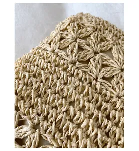 Primer plano del material de paja trenzada en beige, mostrando detalles de crochet floral.