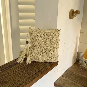 Bolso cruzado tejido beige vista detallada con patrón de ganchillo complejo y borlas elegantes.