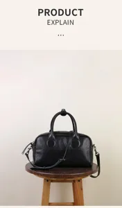Black leather Boston bag detail showing textured finish, dual top handles and strap.