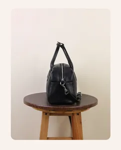 Side detail view of black leather Boston bag showing zipper and handle construction.