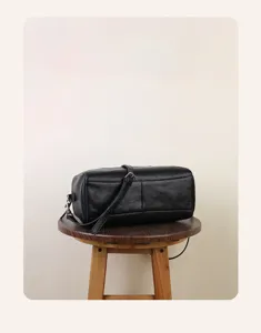 Detail view of the black leather Boston pillow bag showing the fine texture and strap.
