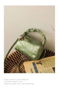 Close-up of Chinese style green satin pillow bag with pleated handle and vintage floral print.