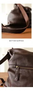 Detailed view of brown genuine leather bag, showing fine stitching and metal zipper hardware.