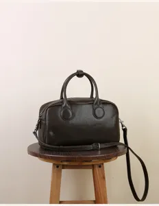 Detail view of retro dark brown Boston bag, classic pillow handbag with shoulder strap.