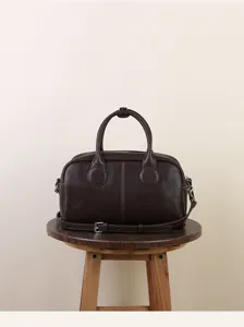 Close-up detail of retro brown leather Boston bag showcasing premium texture and hardware.