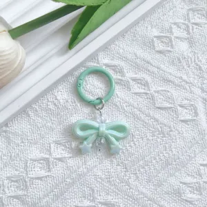 Close-up detail of the light green bow keychain pendant, showing the glossy texture and metal ring.