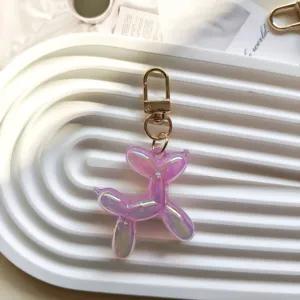 Close-up detail of a cute iridescent purple balloon dog keychain with gold hardware.