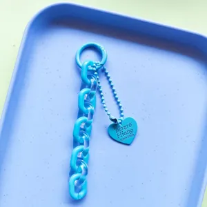 Close-up detail of blue acrylic chain keyring and heart pendant. Perfect bag and phone charm.