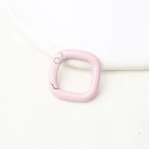 Gedetailleerde close-up van een lichtroze vierkante metalen veergesp voor knutselaccessoires.