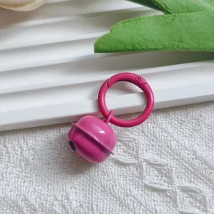 Pink metal bell pendant close up, cute keychain accessory with spring ring DIY charm details.
